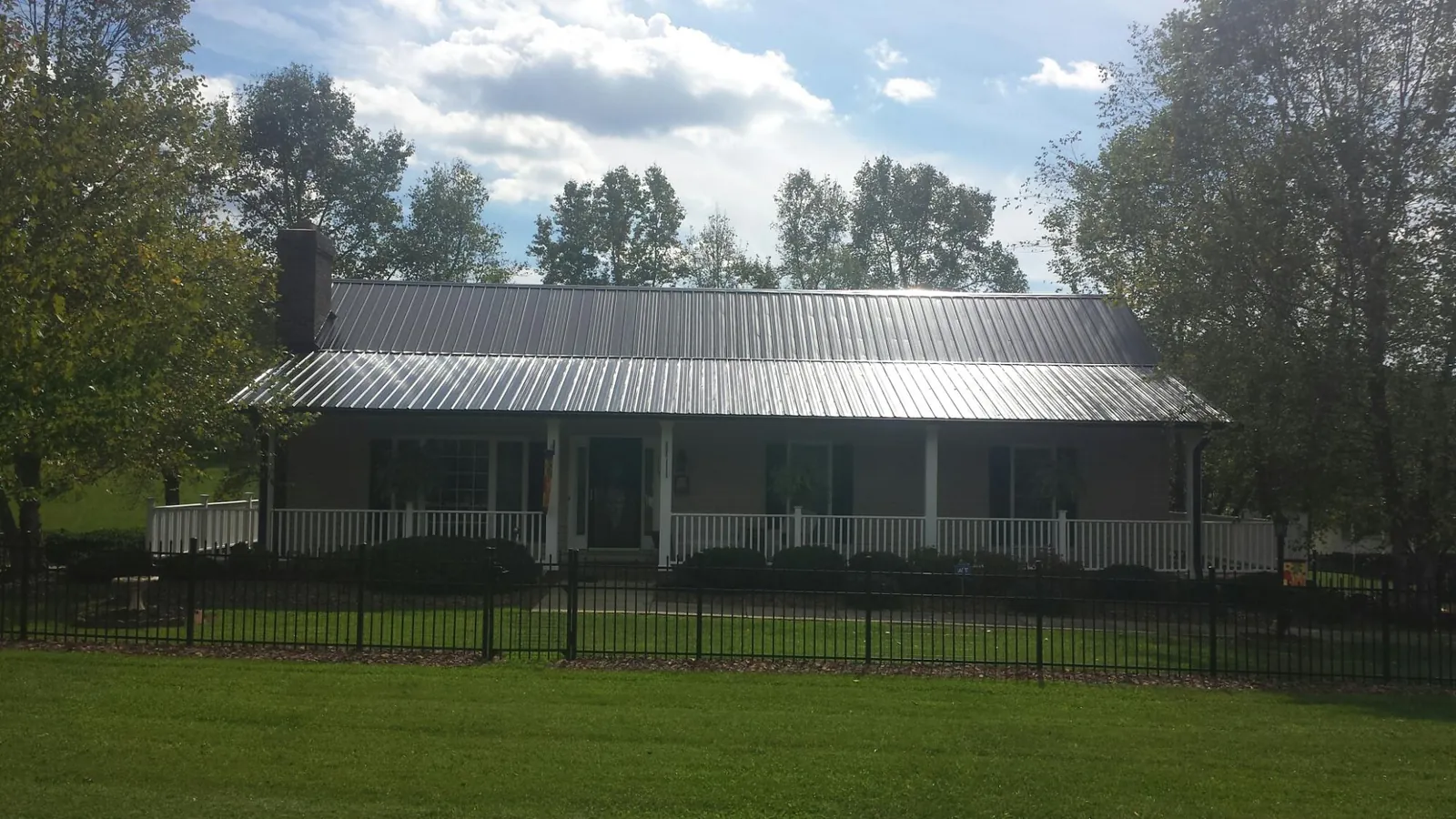 Gray metal roof on a brick ranch with a full width front porch — Gutter Guard Installation work by our crew in Barrington