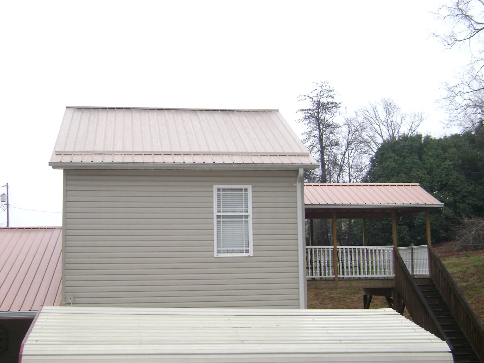 Tan metal roofs on a two story addition and attached porch, from a Roof Replacement job in Barrington